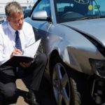 An insurance adjuster investigating accident damage on a vehicle.