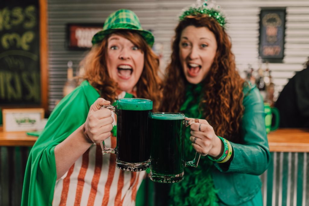 Two women celebrate St. Patrick's day with green beer.