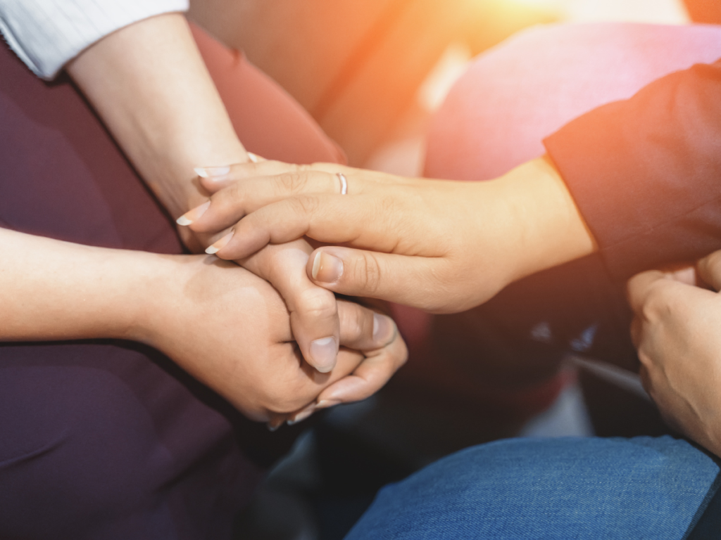 Mental Health focus. Two people sitting on the floor and touching hands in support