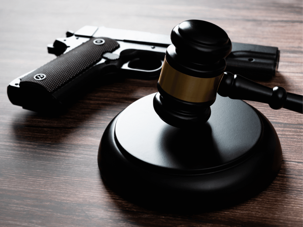 A gun right on the table next to a judges gavel.