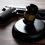 A gun right on the table next to a judges gavel.