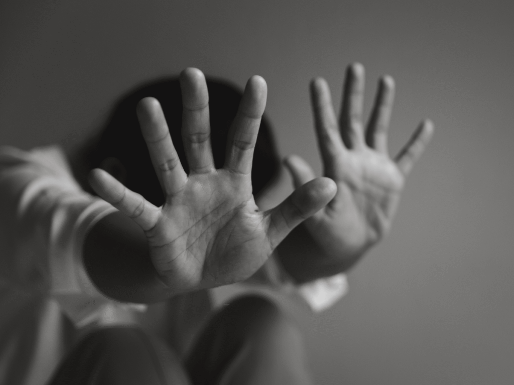 Person hiding their face by holding up open palms