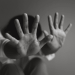 Person hiding their face by holding up open palms