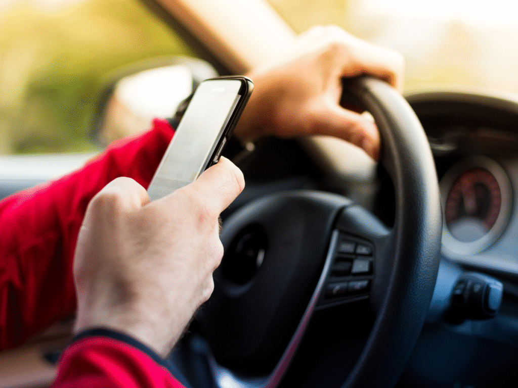 A driver holding and operating a cell phone while driving, illustrating the cause of a distracted driving injury claim Wyoming.