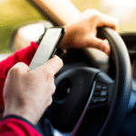 A driver holding and operating a cell phone while driving, illustrating the cause of a distracted driving injury claim Wyoming.