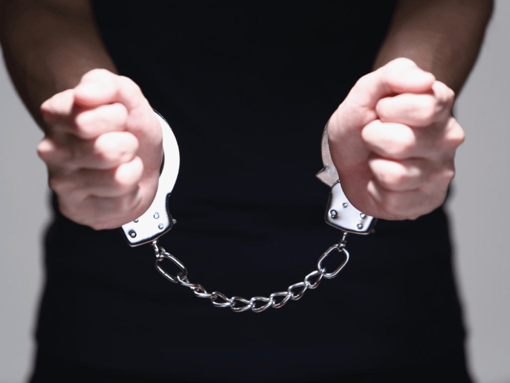 Close-up of a person's hands in handcuffs being held out, illustrating the serious nature of criminal conspiracy charges Wyoming.