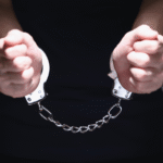 Close-up of a person's hands in handcuffs being held out, illustrating the serious nature of criminal conspiracy charges Wyoming.