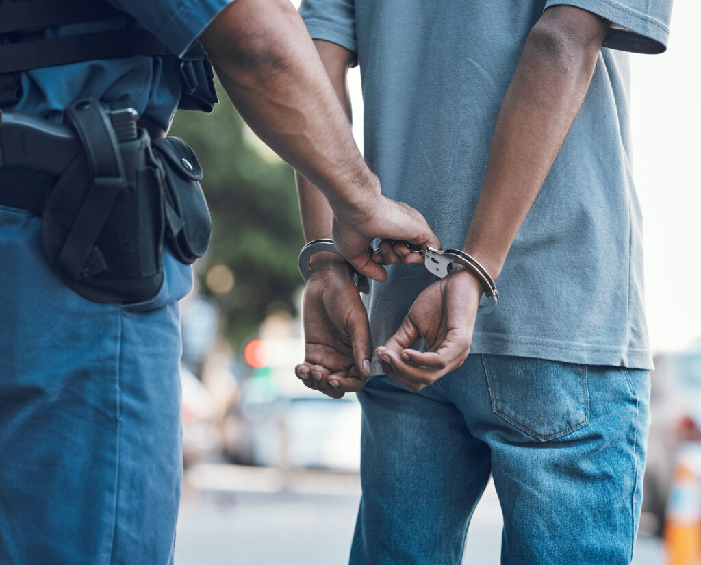 Close-up of a person in handcuffs with their hands restrained behind their back, representing an arrest and the legal consequences of criminal charges in Wyoming.
