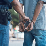 Close-up of a person in handcuffs with their hands restrained behind their back, representing an arrest and the legal consequences of criminal charges in Wyoming.