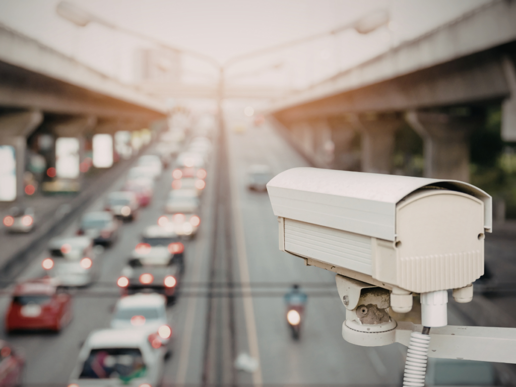 A roadside surveillance camera overlooks a busy roadway with traffic moving beneath an overpass, illustrating how video footage can capture critical evidence in personal injury and accident cases.