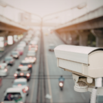 A roadside surveillance camera overlooks a busy roadway with traffic moving beneath an overpass, illustrating how video footage can capture critical evidence in personal injury and accident cases.