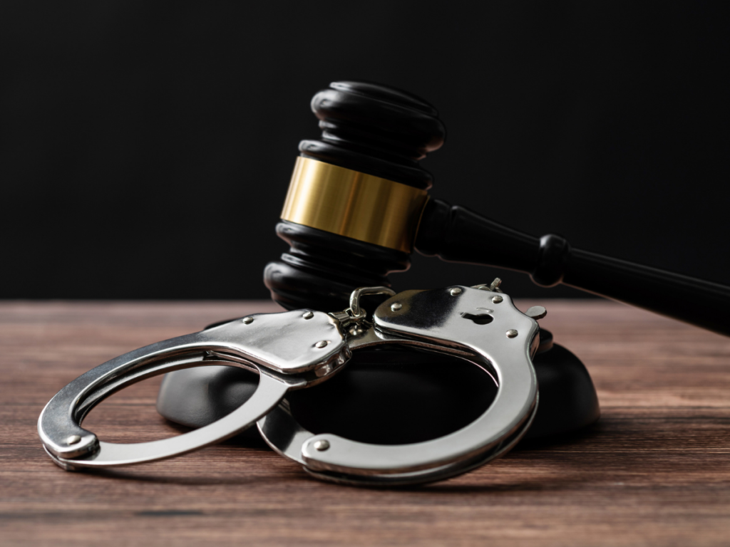 A close-up of handcuffs beside a judge’s gavel, symbolizing the serious legal consequences and criminal charges that can arise from domestic violence accusations—even in cases where the allegations may be disputed or false.