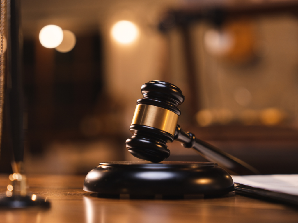 Close-up of a judge’s gavel resting on a sound block inside a courtroom, symbolizing criminal court proceedings, plea negotiations, and legal decision-making.