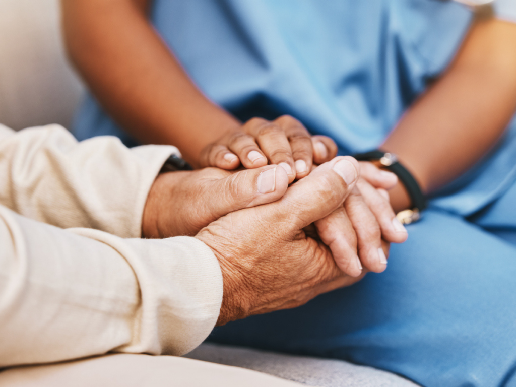 Close-up of a caregiver gently holding an elderly resident's hands, illustrating a blog about recognizing financial exploitation and protecting nursing home residents from elder financial abuse in Wyoming.