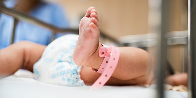 newborn baby wearing diaper and hospital bracelet